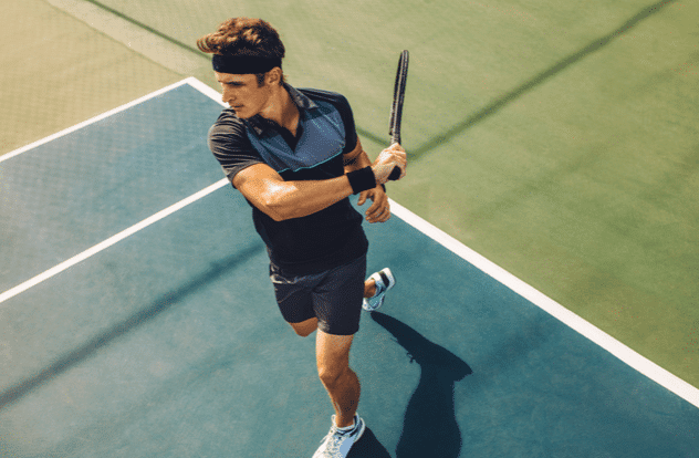 Focused young male tennis player hitting a forehand.