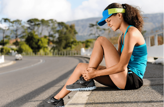 runner with ankle injury holds foot to reduce pain.